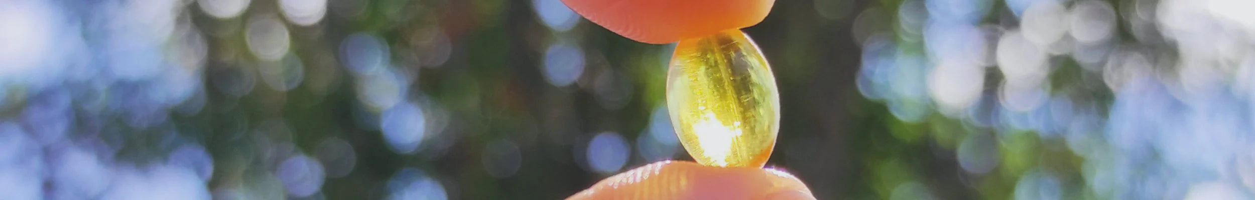 Two yellow jelly beans held between fingers with a blurred natural background