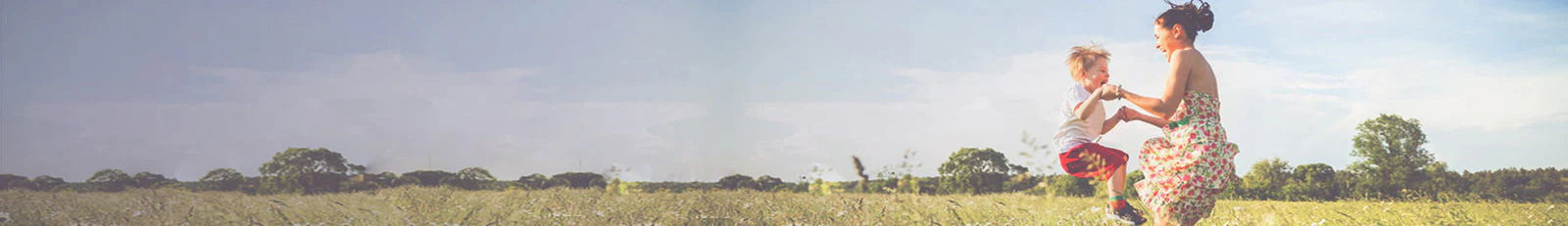 Woman and child playing in a field with a clear sky