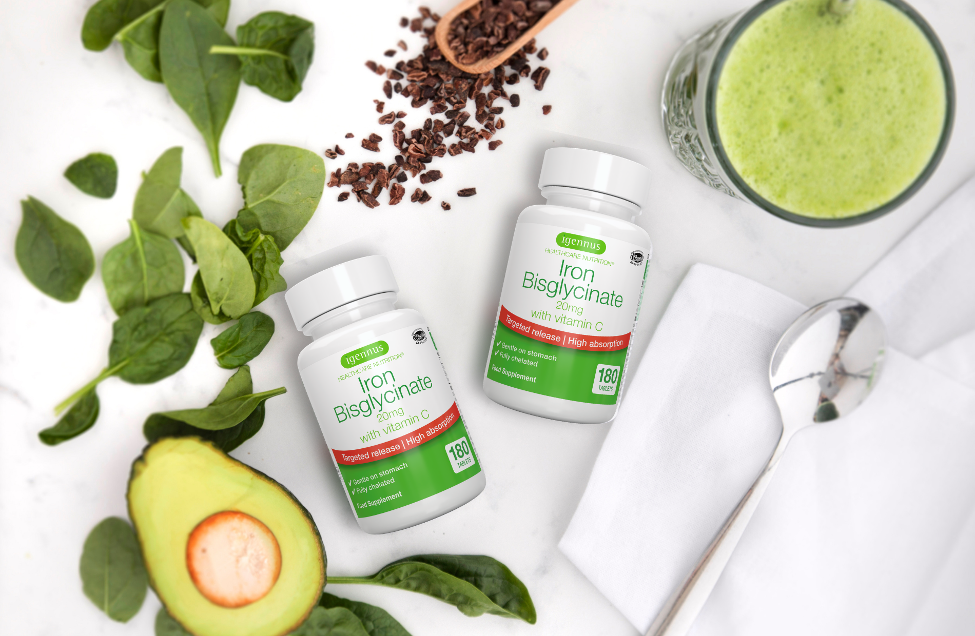 Supplement bottles with greenery, avocado, and a smoothie on a white background