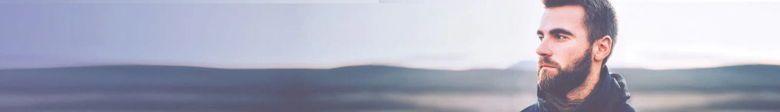 Man with a beard standing in a field with a blurred background