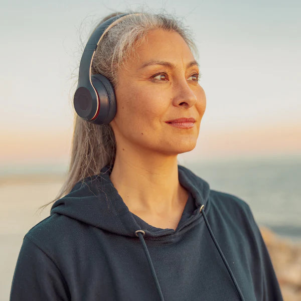 Woman wearing headphones with a blurred beach background