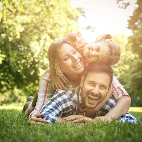 Family of three lying on grass with trees in the background