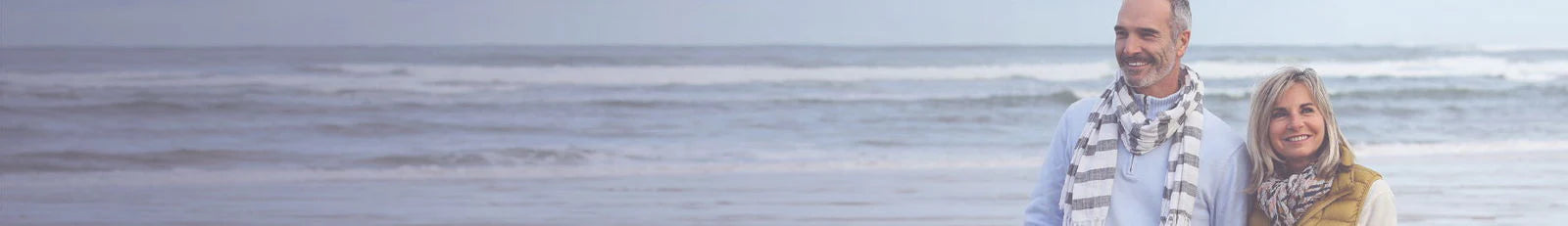 Man and woman standing on a beach with ocean waves in the background
