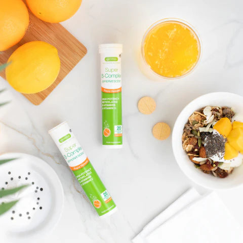 Supplement bottles, oranges, and a bowl of granola on a white surface