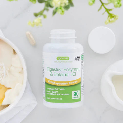Supplement bottle labeled 'Digestive Enzymes & Betaine HCl' on a light background with blurred food items.