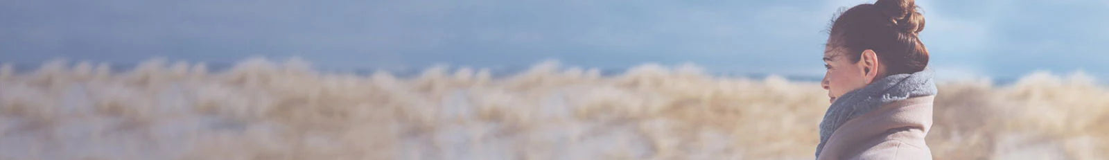 Person standing in a desert landscape with sand dunes and clear sky.