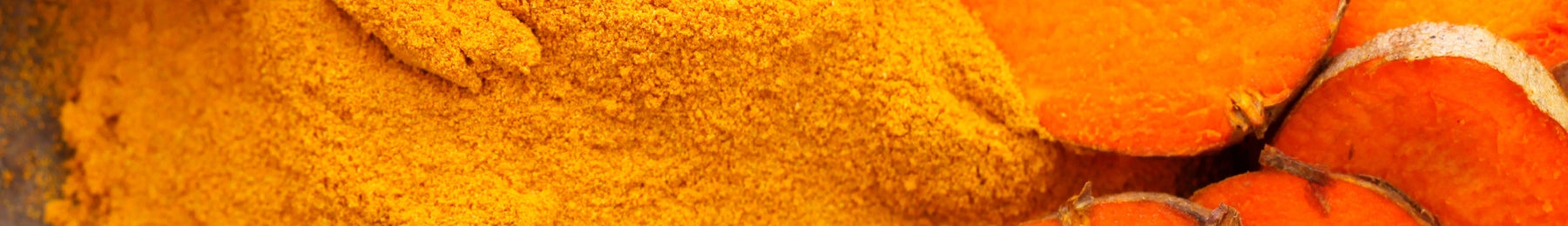 Close-up of turmeric powder with turmeric root in the background