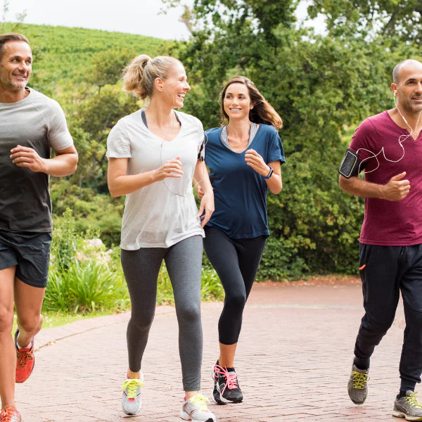 Four people jogging outdoors on a path with greenery in the background