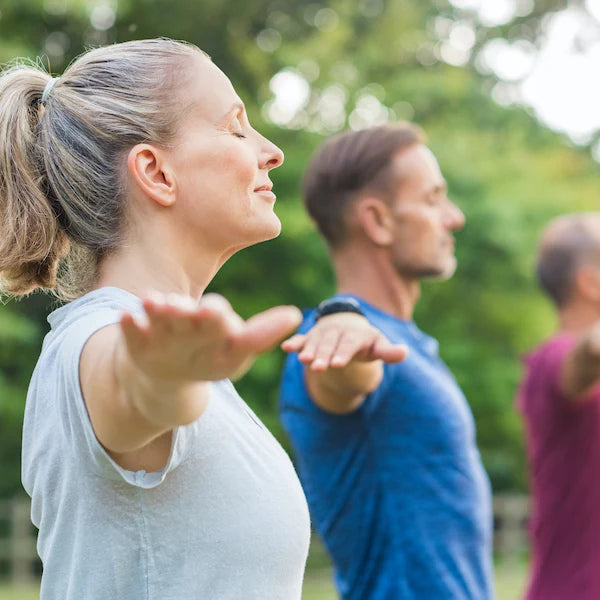 Two people practicing yoga outdoors with a blurred background