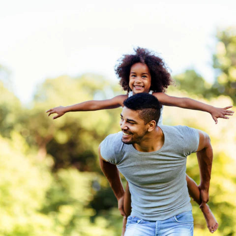 Man carrying a child on his shoulders in a park