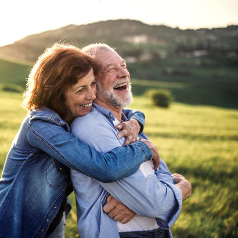 Senior couple embracing in a field with a scenic background
