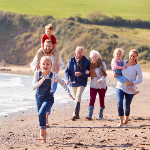 Family of six enjoying a day at the beach with a scenic background.