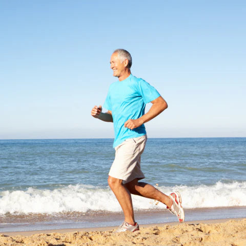 Man running on a beach with ocean waves and clear sky in the background