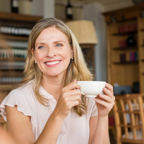 Woman holding a white cup in a cozy indoor setting