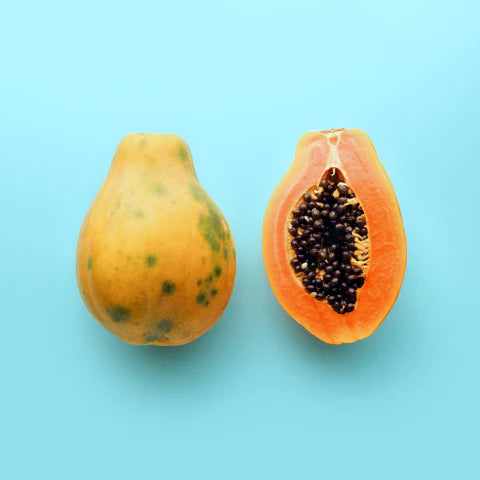 Whole and halved papaya on a light blue background