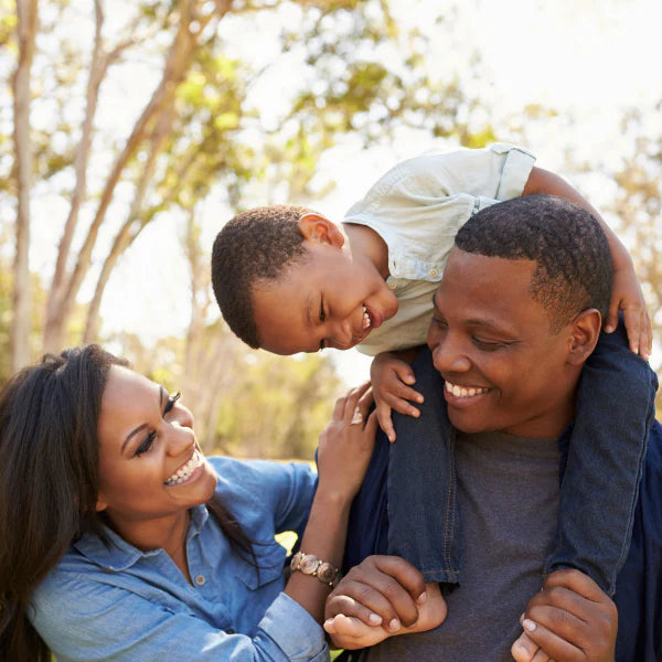 Family of three with a child on father's shoulders in a park setting