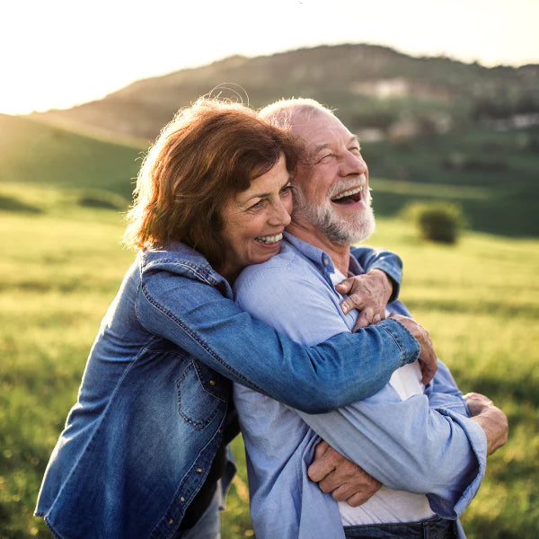 Senior couple embracing in a grassy field with a scenic background