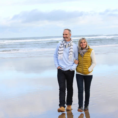 Man and woman standing on a beach with ocean waves in the background