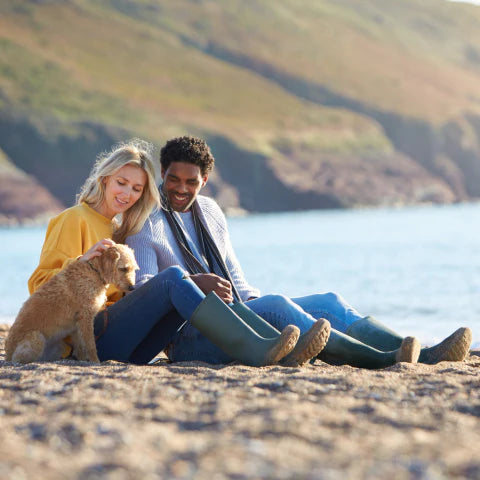 Couple sitting on a beach with a dog, enjoying each other's company.