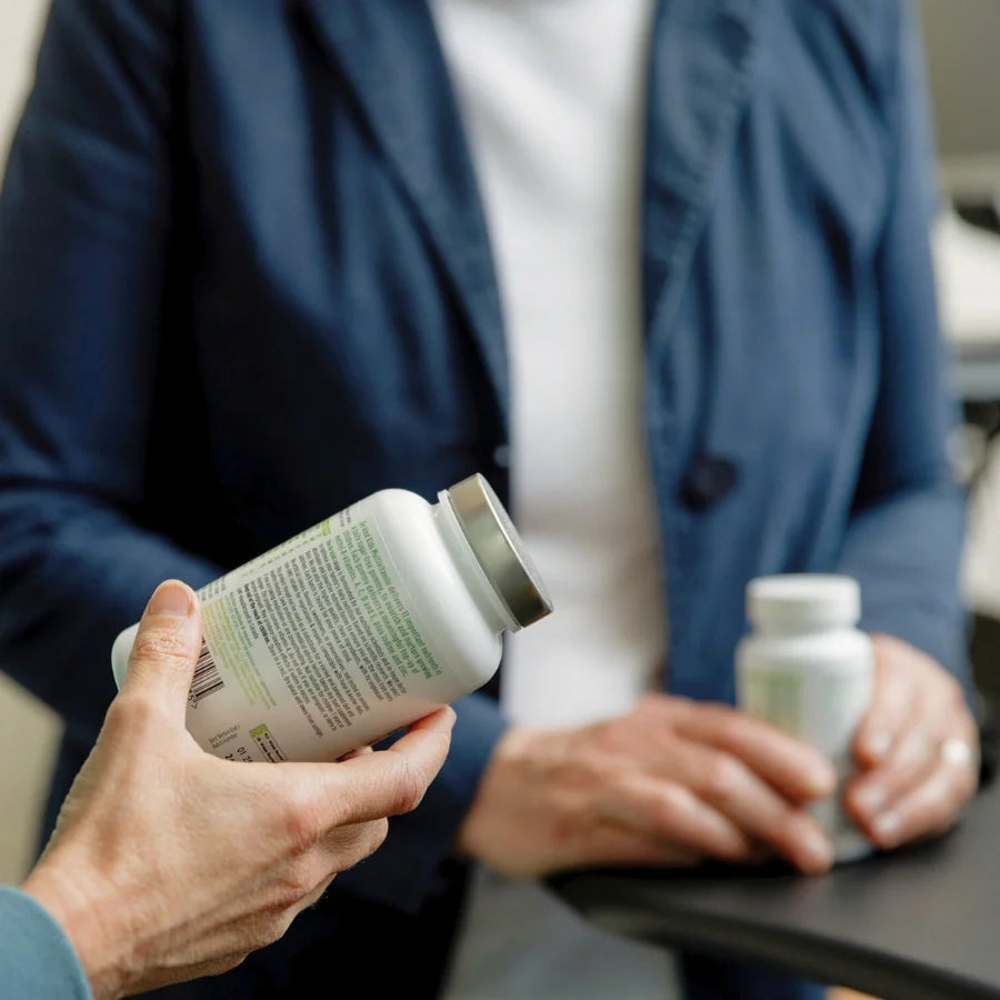 Two people holding supplement bottles in a medical setting