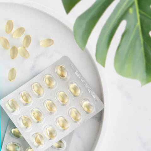 Vitamins or supplements in a white container with green leaves in the background
