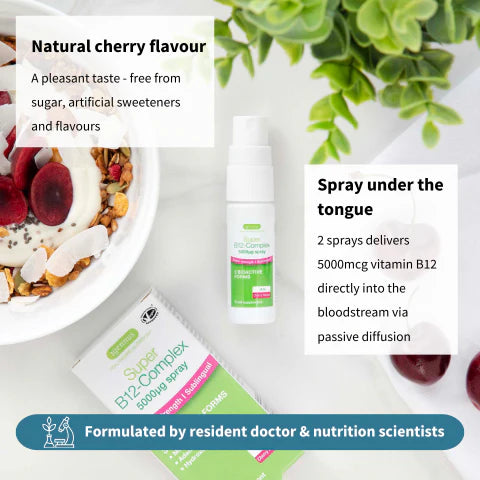 Supplement spray bottle with packaging on a table with a bowl of fruit and a plant in the background.