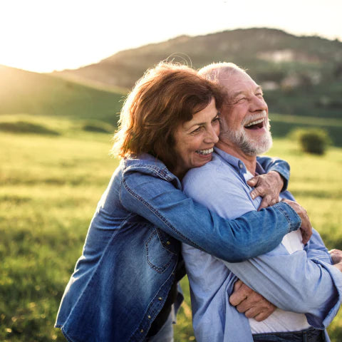 Senior couple embracing in a field with a scenic background