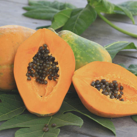 Papaya with green leaves on a wooden surface