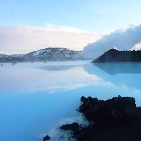 Scenic view of a lake with mountains and clouds in the background