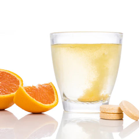 Glass of orange juice with sliced oranges and tablets on a white background