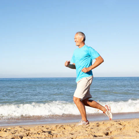 Man jogging on a beach with clear blue sky and ocean.