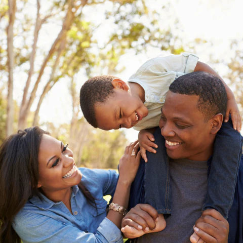 Family of three outdoors with a young boy on his father's shoulders