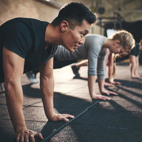 Group of people doing push-ups on a mat outdoors