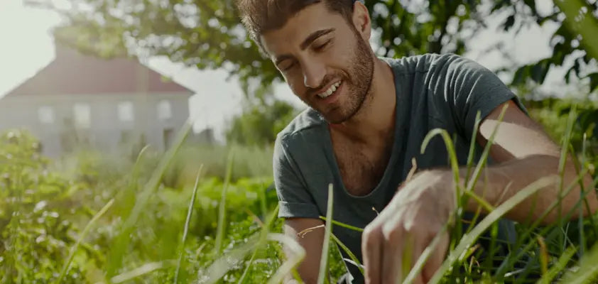 Man kneeling in a grassy area with a blurred background